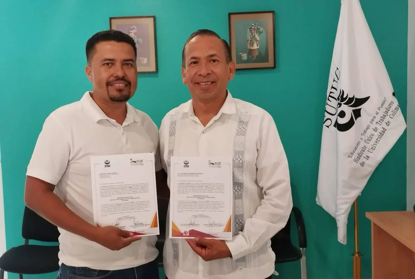 Néstor Álvarez Paredes y Luis Enrique Zamorano Manríquez con sus nombramientos del INDET Colima frente a la bandera del SUTUC